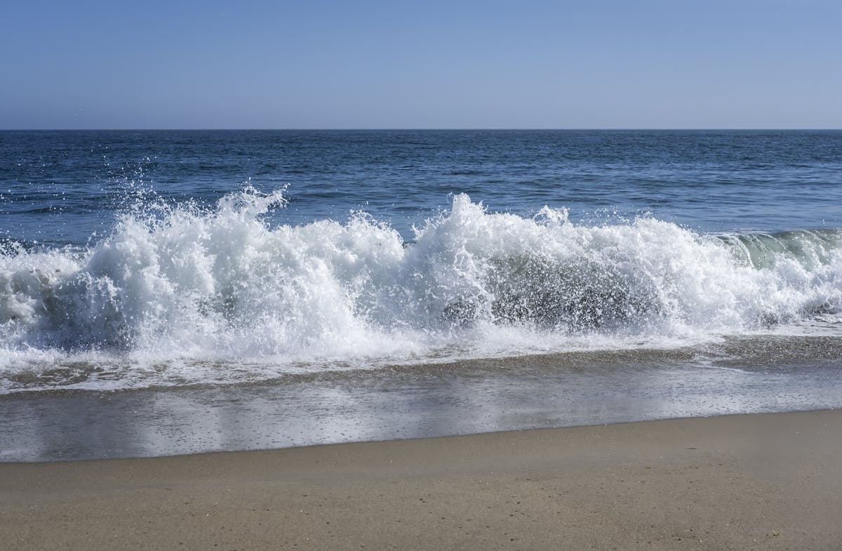 A beach with waves crashing on the shore